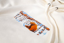 Load image into Gallery viewer, A close up of the design on an off-white hoodie. The design includes a brown bear in a snowy forest.
