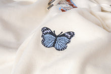 Load image into Gallery viewer, A close up of the embroidered blue and black butterfly on the left shoulder.
