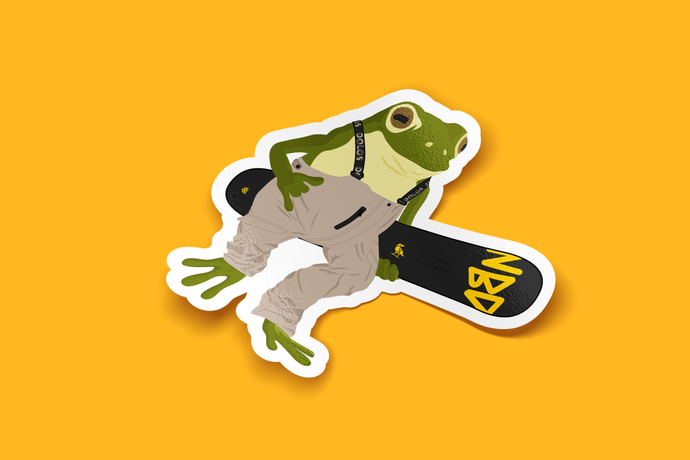 View from an angle - A green and yellow frog wearing tan suspenders and holding a black snowboard with a yellow Dolos bird and NBD in yellow font.