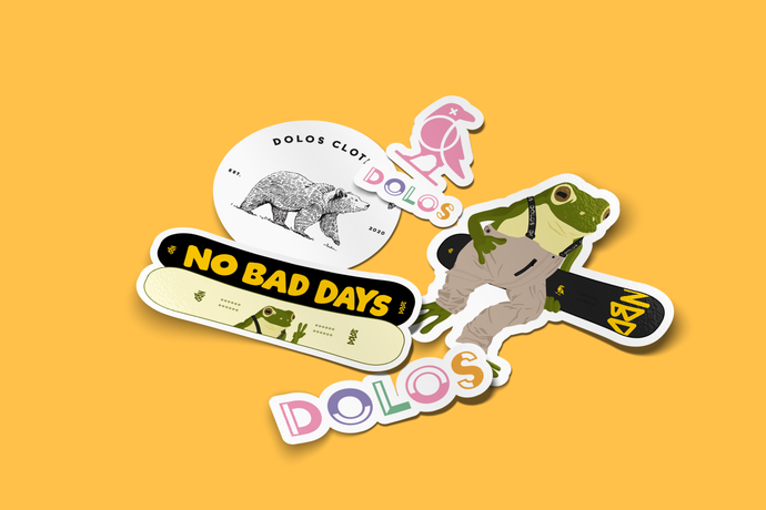 View from an angle - All five Dolos stickers that are sold individually laid out on a yellow backdrop.