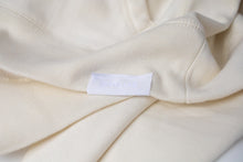 Load image into Gallery viewer, A close up of the pure-white Dolos tag sewn on the left hip.